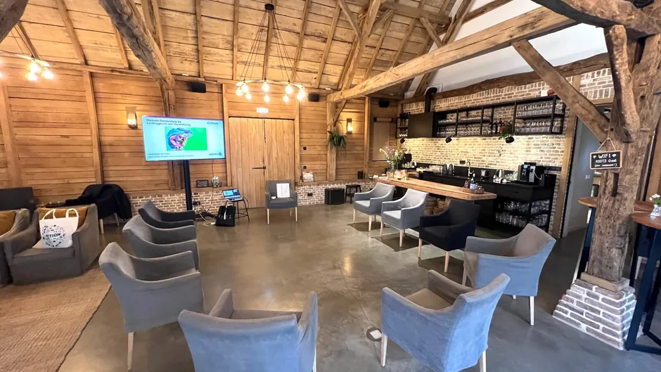 ROOTS Inspiratielocatie in Haaren, een sfeervolle werkruimte met eikenhouten balken en een open kring van fauteuils